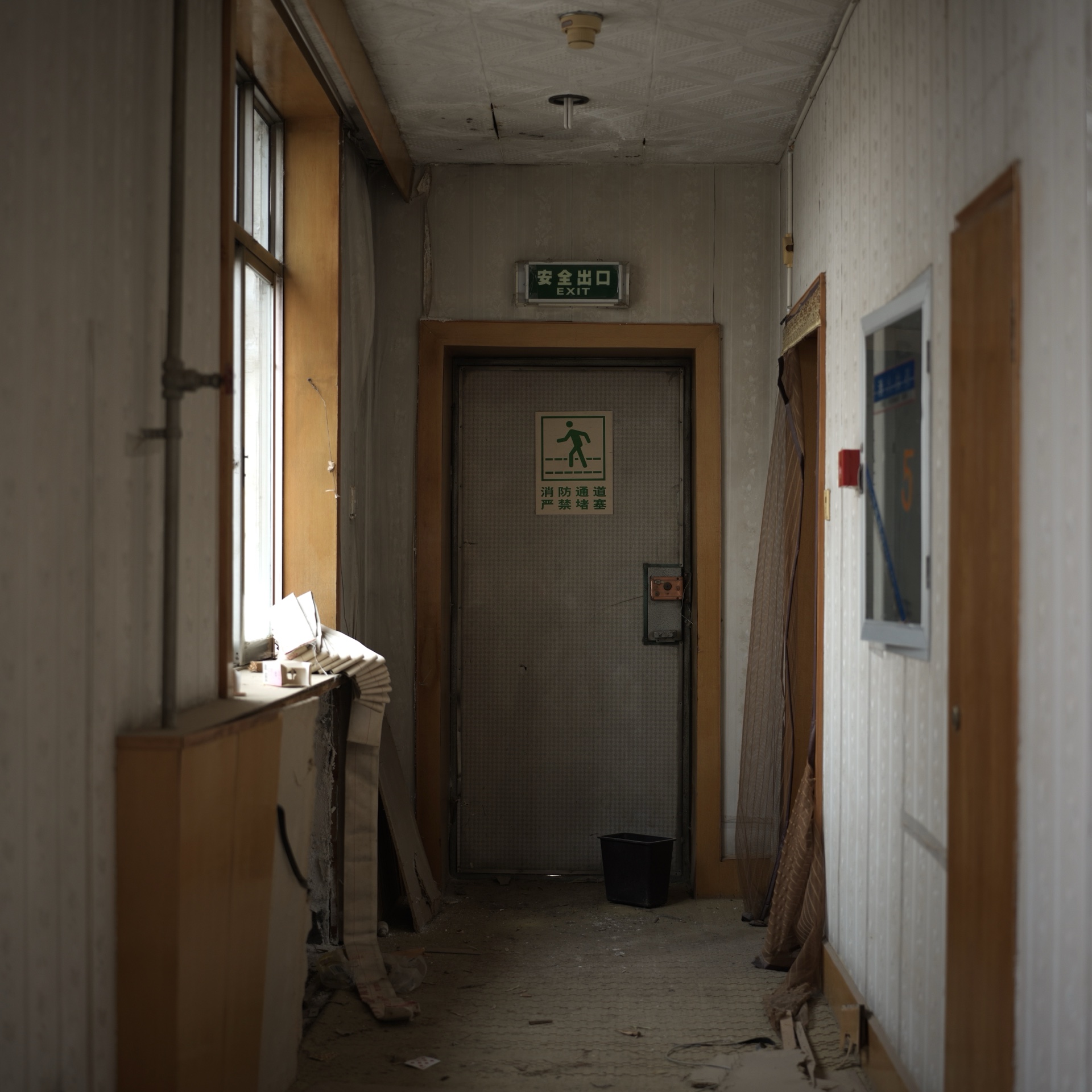 An abandoned corridor ending at an emergency exit door